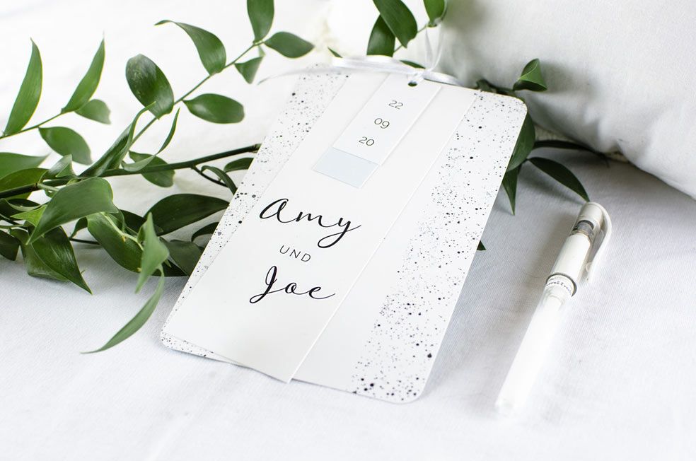 Moderne Hochzeitseinladung mit schwarzen Sprenkeln als Kartenset mit kleinen Anhängern in Mint aus der Serie Amy und Joe von carinokarten
